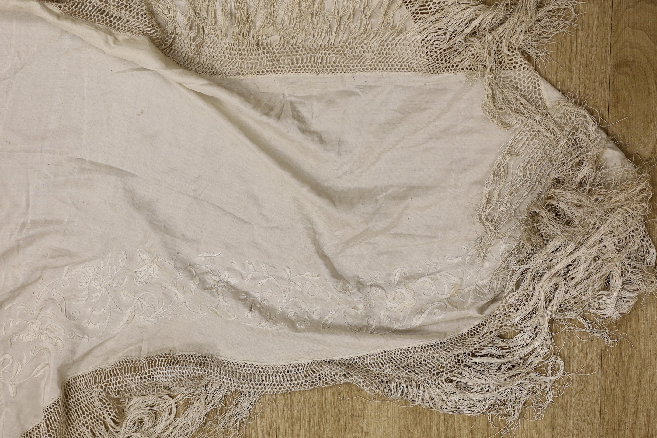 A late 19th/early 20th century Chinese cream silk shawl with cream silk embroidery and fringing, converted to a ladies cape